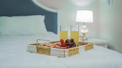 a tray of fruit and two glasses of wine on a bed at Hotel El Imperio Punta Cana in Punta Cana