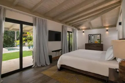 a bedroom with a large bed and sliding glass doors at Villa Laguna, Lush Oasis In Casa De Campo in La Romana