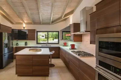a large kitchen with wooden cabinets and a stove at Villa Laguna, Lush Oasis In Casa De Campo in La Romana