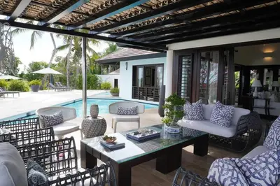a patio with a table and chairs and a pool at Villa Alpes, Exquisite Retreat In Casa De Campo in La Romana