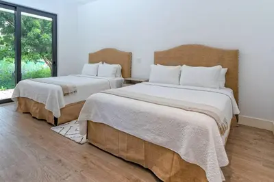 a bedroom with two beds with white sheets and a window at Villa Polos, Prestigious Haven In Casa De Campo in La Romana