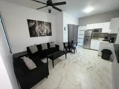 a living room with a black couch and a kitchen at Level suites #2 platinum in Sosúa