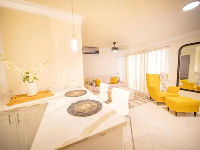 a kitchen and living room with yellow chairs and a table at Garden Condos 21, Modern 1BR APT In Sosua Strip GUEST FRIENDLY in Sosúa