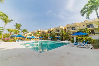 a pool at the resort with chairs and umbrellas at Garden Condos 21, Modern 1BR APT In Sosua Strip GUEST FRIENDLY in Sosúa