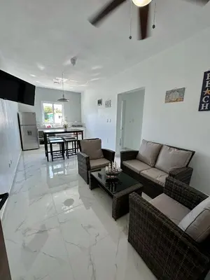 a living room with couches and a table and a kitchen at Sunrise ApartaHotel in El Manguito