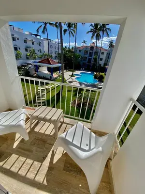 a balcony with a white chair and a swimming pool at The Best Place in los Corales RD Arenas De B in Punta Cana