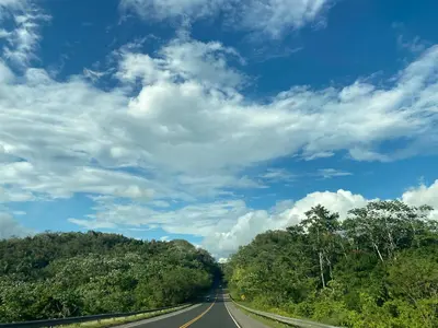 an empty road under a blue sky with clouds at River 1 Basili in Santa Bárbara de Samaná