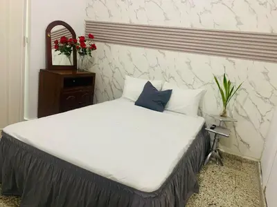 a bedroom with a large bed with white sheets and blue pillows at Tropical Estudio En El Centro De La Ciudad in San Felipe de Puerto Plata