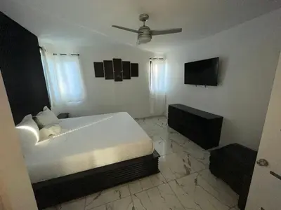a bedroom with a white bed and a television at LEVEL suites #4 OMEGA in Sosúa