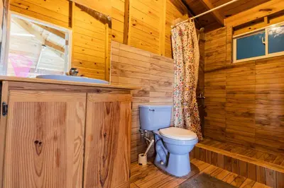 a wooden bathroom with a toilet and a sink at Mango House Big air studio in Cabarete