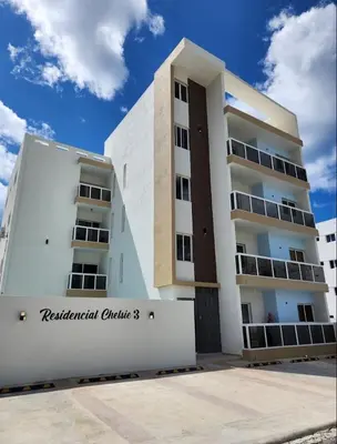 a white apartment building with a sign in front of it at Apartamento completo en Bayahibe in Bayahibe