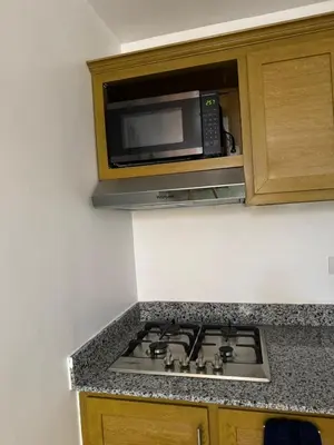 a microwave oven above a stove in a kitchen at Departamento en el centro in Santiago de los Caballeros