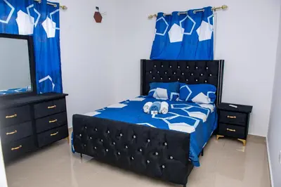 a bedroom with a bed with blue sheets and blue curtains at Luxury Aparment Bonao in Bonao