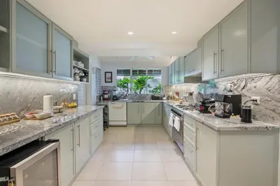 a large kitchen with white cabinets and marble counter tops at Cozy Private Family Villa at Casa de Campo - Pool, BBQ, Golf Cart in La Romana