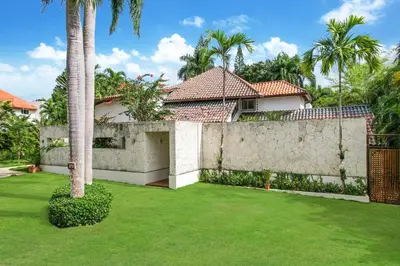 a house with a retaining wall and a green yard at Cozy Private Family Villa at Casa de Campo - Pool, BBQ, Golf Cart in La Romana