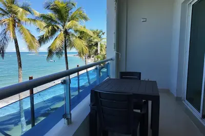 a balcony with a table and a view of the ocean at Beachfront Cabarete Apartment in Cabarete