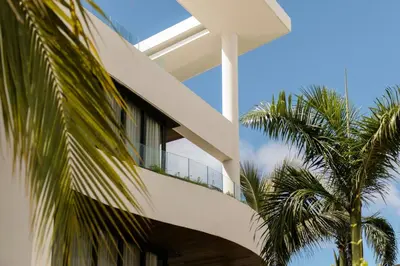 a white house with palm trees in front of it at Donoma Las Terrenas Beach Hotel & Spa, Autograph Collection in Las Terrenas