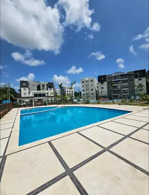 a large swimming pool with buildings in the background at Apartamento con terraza y jacuzzi privado in Santo Domingo