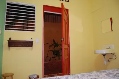 a bedroom with a red door and a sink at La Choza Guesthouse in Santo Domingo