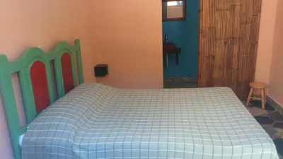 a bedroom with a bed with a green and white bedspread at La Choza Guesthouse in Santo Domingo