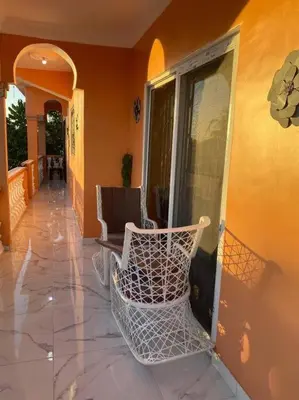 a rocking chair sitting on a porch of a house at Modern Country Side Lux Apt in La Ceibita