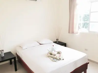 a bedroom with a bed with white sheets and a window at Costambar Beachfront Stay with Pool in San Felipe de Puerto Plata