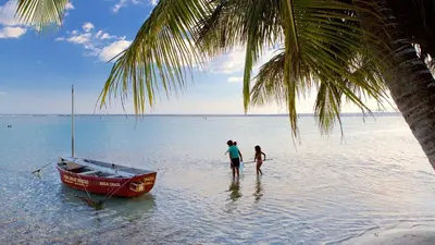 two people standing in the water next to a boat at Boca del Mar III, apartamento 707 in Cuevas