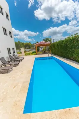 a blue swimming pool with chairs and a gazebo at Modern 2BR Apartment 3 Min from Airport with Free Parking in Sosúa