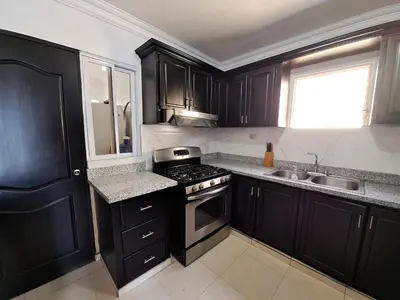 a kitchen with black cabinets and a stove and a sink at Centrico con yacuzzi privado in Santiago de los Caballeros