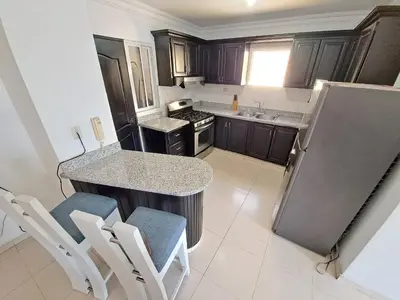 a small kitchen with a counter and chairs in it at Centrico con yacuzzi privado in Santiago de los Caballeros
