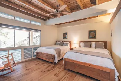 two beds in a room with wood floors and windows at Majestic villa with stunning views in Jarabacoa in Buena Vista