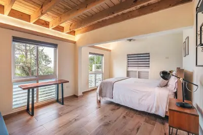 a bedroom with a bed and a desk and windows at Majestic villa with stunning views in Jarabacoa in Buena Vista