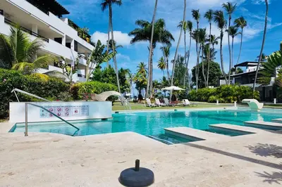 a swimming pool at a resort with palm trees at Aligio Beachfront Resort & Spa in Las Terrenas