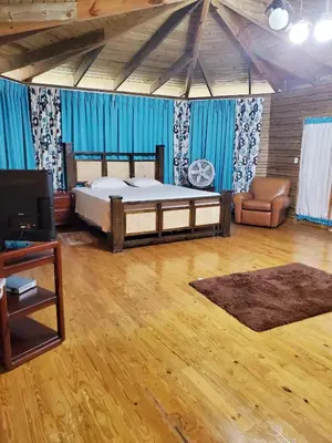 a bedroom with a bed and a couch and blue curtains at Villas Las Neblinas in Constanza