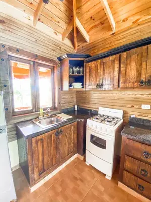 a kitchen with wooden cabinets and a white stove top oven at Villas Las Neblinas in Constanza