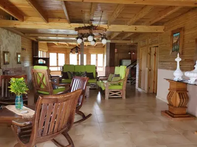 a living room with wooden ceilings and green chairs at Villas Las Neblinas in Constanza