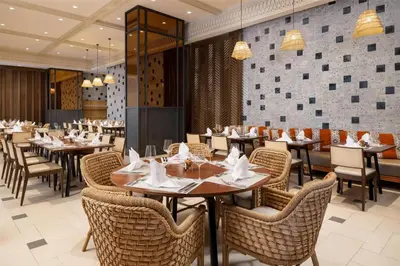 a restaurant with tables and chairs and a tv at Hotel Santiago, Curio Collection By Hilton in Santiago de los Caballeros