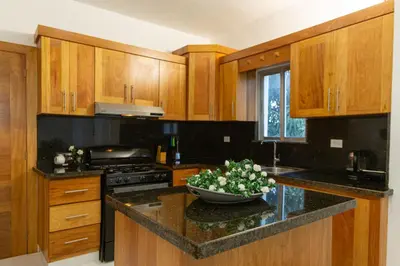 a kitchen with wooden cabinets and a bowl of flowers on the counter at Crown ll-3 Bedrooms-Pool-Close to everything! in San Felipe de Puerto Plata