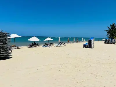a beach with people sitting under umbrellas and the ocean at Divine Stay 3 Bedroom One minute from the beach on the malecon in San Felipe de Puerto Plata