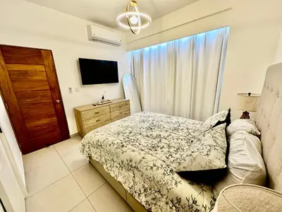 a bedroom with a bed and a dresser and a window at Acogedor Apartamento en JUAN DOLIO in Los Corrales