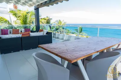 a wooden table and chairs on a balcony with the ocean at Brisas del norte in Sosúa