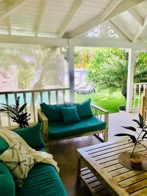 a porch with a green couch and a table at Tropical Villa 4Bedroom 3Baths and Pool Near Beach in Las Terrenas