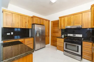 a kitchen with wooden cabinets and stainless steel appliances at Crown lll with Pool -3 Bedrooms close to Everything in Puerto Plata