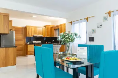 a kitchen with a glass table and blue chairs at Crown lll with Pool -3 Bedrooms close to Everything in Puerto Plata