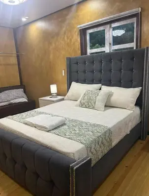 a large bed with a large padded headboard in a bedroom at Villa Naturaleza y confort in Santiago de los Caballeros