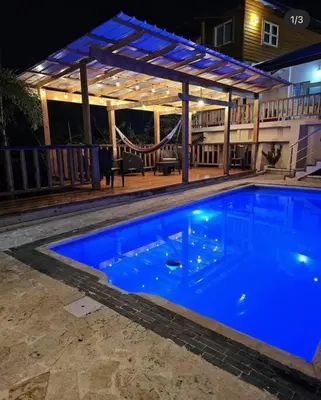 a large blue swimming pool with a pergola at Villa Naturaleza y confort in Santiago de los Caballeros