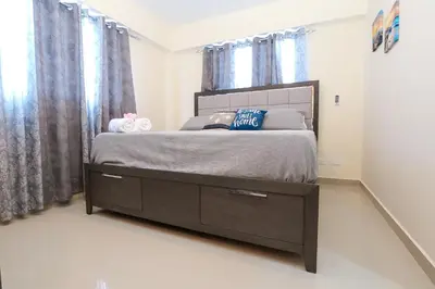 a bedroom with a bed with a dresser and curtains at Edificio Amber 1 in San Cristóbal