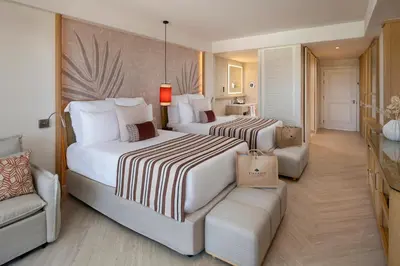 a hotel room with two beds and a couch at Dreams Playa Esmeralda Resort & Spa - All Inclusive in Miches