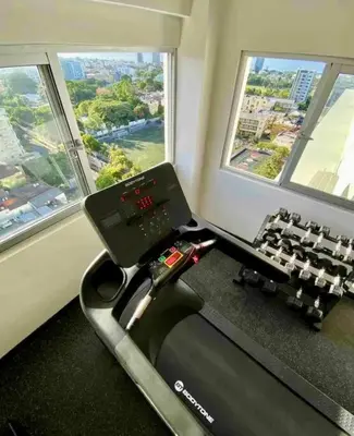 a gym with a treadmill and two windows at Apartmento en el corazón de la ciudad con piscina infinita y vista al mar in Santo Domingo
