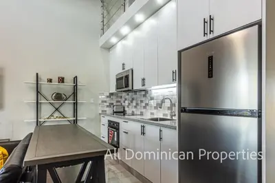 a kitchen with a stainless steel refrigerator and a table at Hill Side Condos - Hispaniola in Sosúa